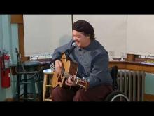 Charlie Mosbrook playing guitar in his wheelchair