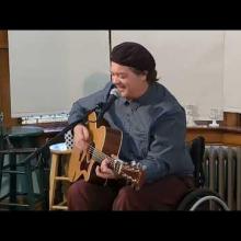 Charlie Mosbrook playing guitar in his wheelchair
